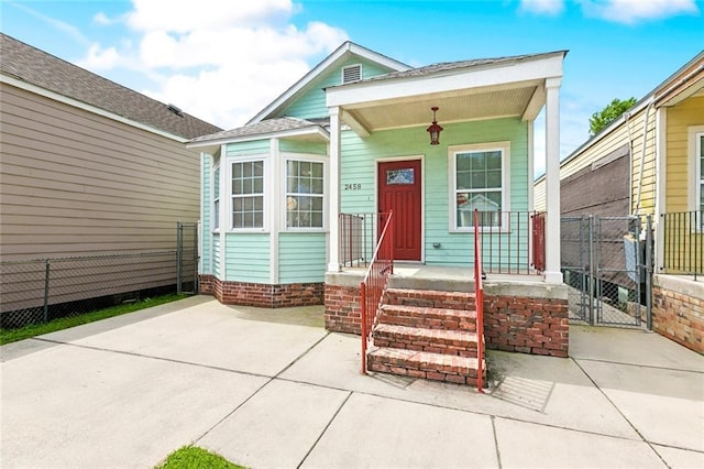 shotgun-style home with a porch, a gate, fence, and roof with shingles