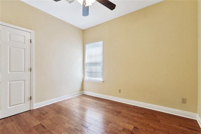 unfurnished room with a ceiling fan, wood finished floors, and baseboards