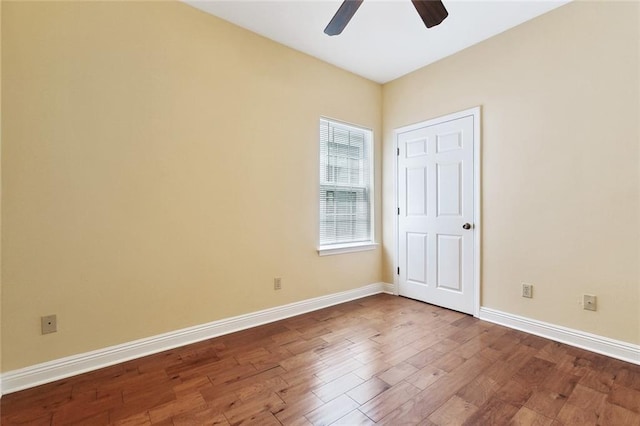 spare room featuring a ceiling fan, dark wood-type flooring, and baseboards