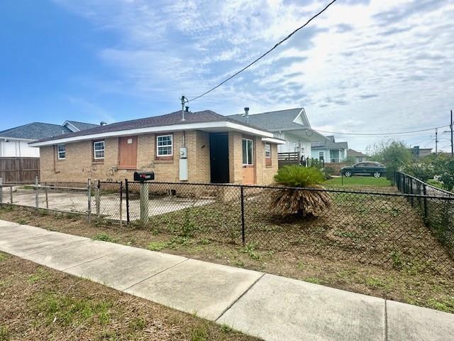 view of front facade featuring brick siding and a fenced front yard