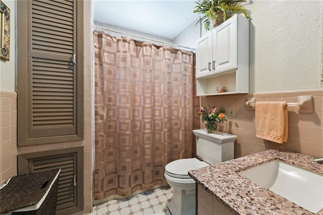 510 Nursery Ave, Metairie, LA 70005 - bathroom featuring tile walls, toilet, a shower with curtain, a wainscoted wall, and tile patterned floors