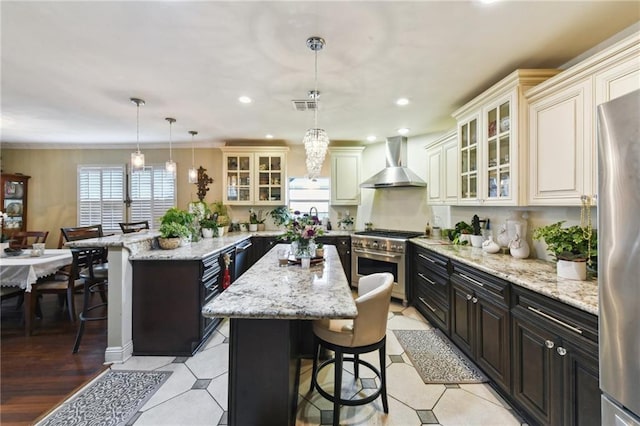 510 Nursery Ave, Metairie, LA 70005 - kitchen with wall chimney range hood, stainless steel appliances, a center island, a kitchen breakfast bar, and recessed lighting