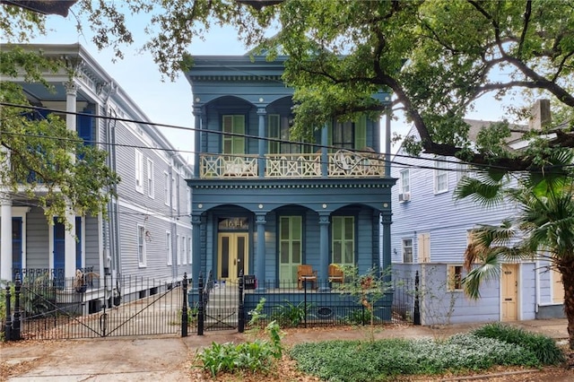 1614 Governor Nicholls St Unit 1, New Orleans, LA 70116 - italianate-style house featuring a porch, a balcony, a gate, and a fenced front yard