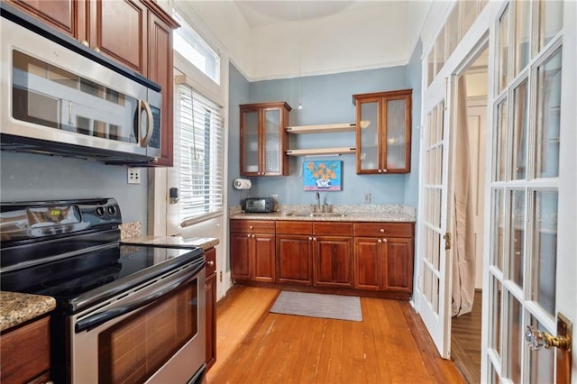 1614 Governor Nicholls St Unit 1, New Orleans, LA 70116 - kitchen with appliances with stainless steel finishes, a sink, light wood-style floors, brown cabinetry, and french doors