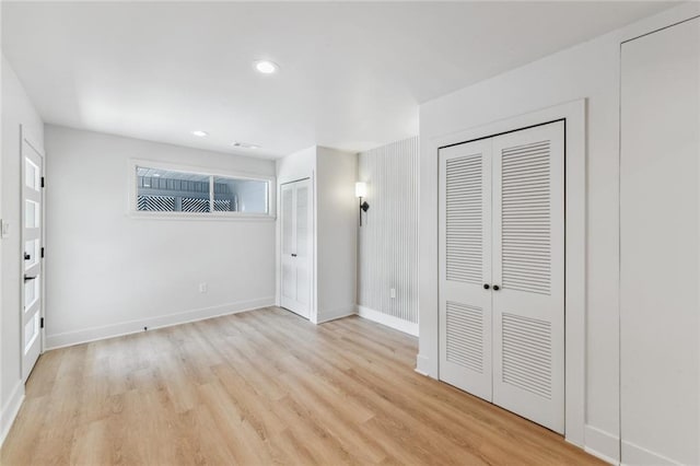 unfurnished bedroom featuring two closets, light wood-type flooring, baseboards, and recessed lighting