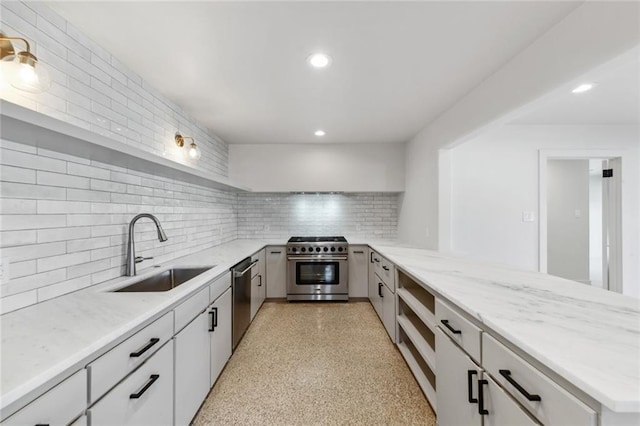 kitchen with appliances with stainless steel finishes, a sink, a peninsula, backsplash, and light stone countertops