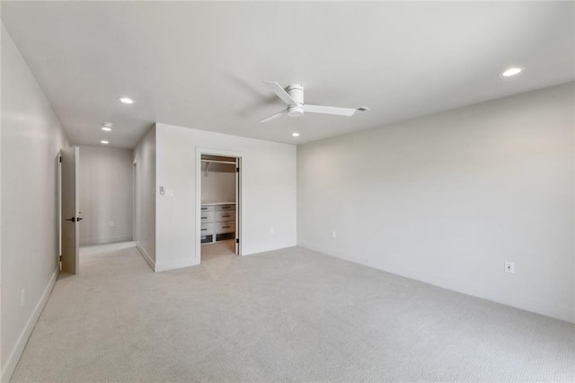 unfurnished bedroom featuring recessed lighting, light carpet, baseboards, a spacious closet, and a ceiling fan