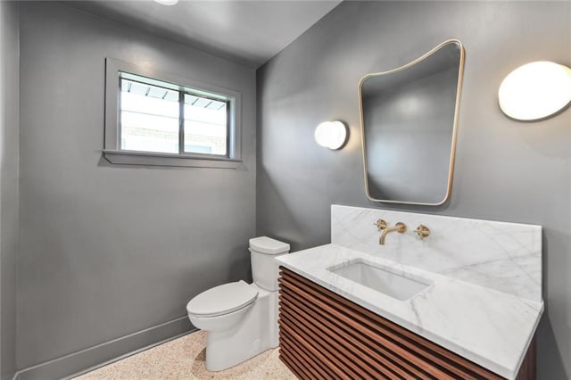 bathroom featuring speckle patterned floor, toilet, vanity, and baseboards