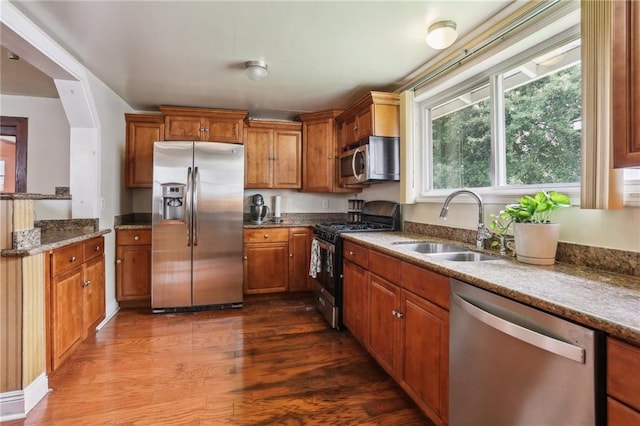 922 Lamanche St, New Orleans, LA 70117 - kitchen with appliances with stainless steel finishes, a sink, brown cabinetry, and dark wood-style flooring