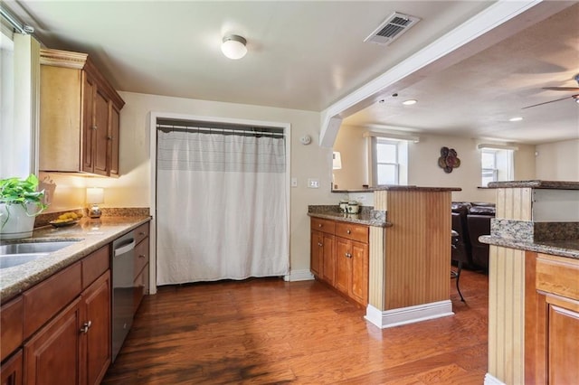 922 Lamanche St, New Orleans, LA 70117 - kitchen featuring dark wood finished floors, brown cabinetry, a breakfast bar, stone countertops, and recessed lighting