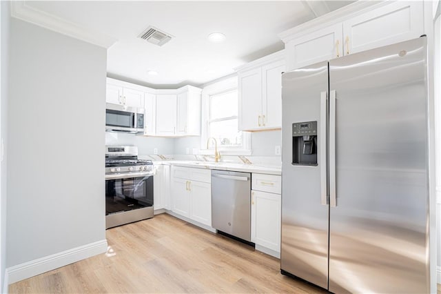 3827 Catherine Ave, Metairie, LA 70001 - kitchen featuring stainless steel appliances, light wood-type flooring, white cabinets, a sink, and crown molding