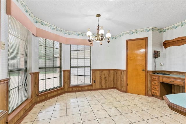 1 Fairfax Ct, Marrero, LA 70072 - unfurnished dining area with a textured ceiling, a chandelier, a wainscoted wall, wallpapered walls, and light tile patterned flooring