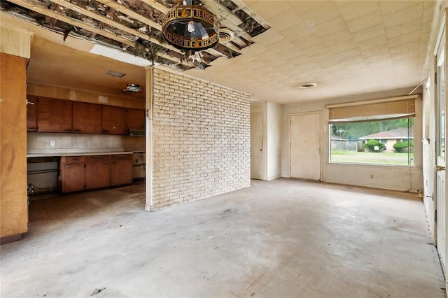 121 Saint Nicholas St, Luling, LA 70070 - unfurnished living room featuring concrete floors and brick wall