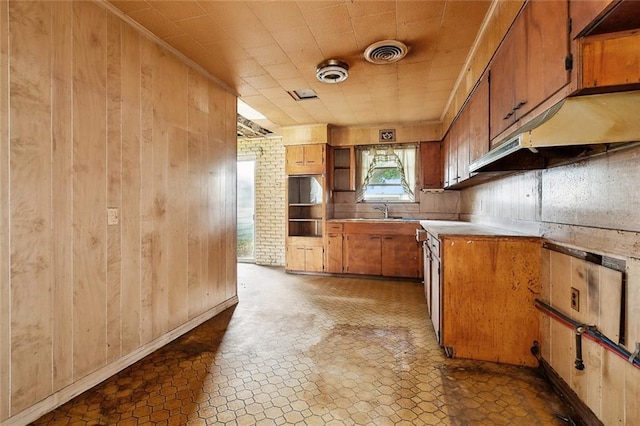 121 Saint Nicholas St, Luling, LA 70070 - kitchen with a warming drawer, wood walls, brown cabinetry, light countertops, and a sink