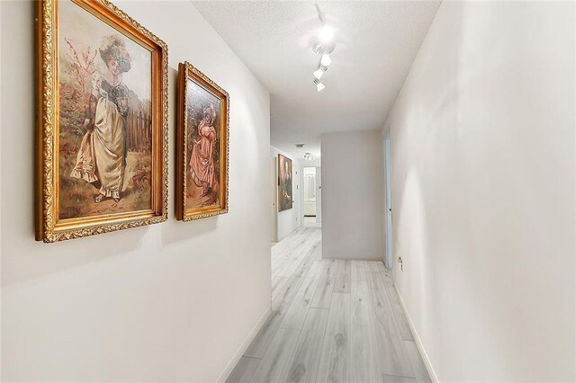 1750 Saint Charles Ave Unit 531, New Orleans, LA 70130 - hall featuring light wood-style flooring, track lighting, baseboards, and a textured ceiling