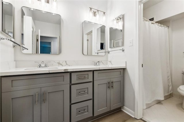 full bath with toilet, double vanity, baseboards, and a shower with curtain