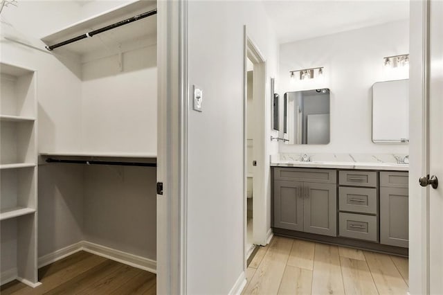 1750 Saint Charles Ave Unit 531, New Orleans, LA 70130 - bathroom with wood finished floors, a walk in closet, double vanity, and baseboards