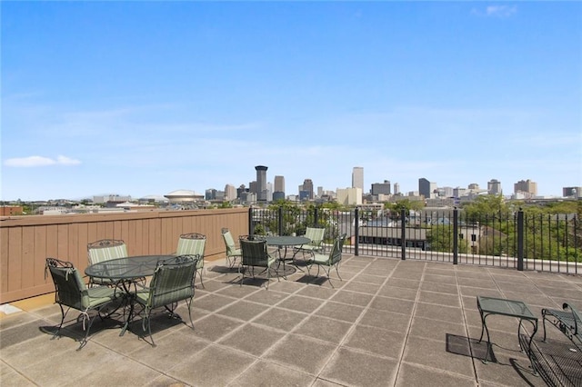 view of patio featuring outdoor dining area, a skyline view, and fence