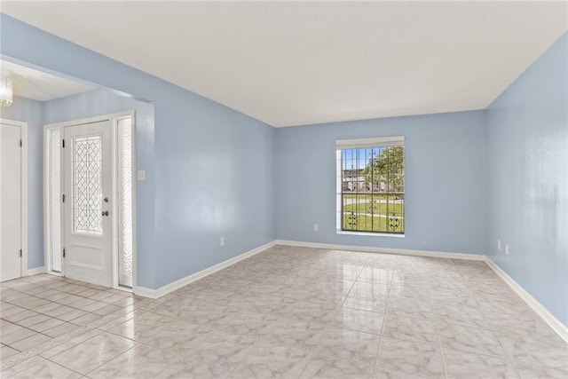 foyer featuring marble look tile flooring and baseboards