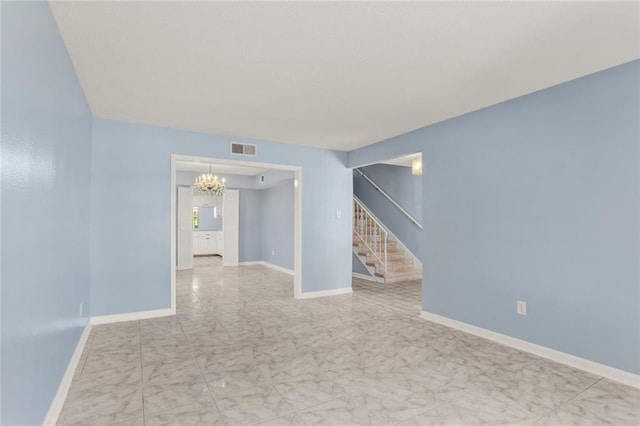 empty room with stairs, a chandelier, marble look tile flooring, and baseboards