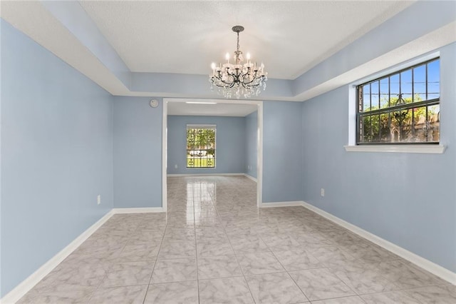 spare room with a chandelier, marble finish floors, and baseboards