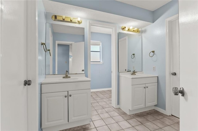 bathroom featuring tile patterned floors, two vanities, and baseboards
