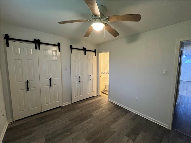 3278 Glen Eagle Ln, Kenner, LA 70065 - unfurnished bedroom featuring a barn door, dark wood-type flooring, baseboards, and a ceiling fan
