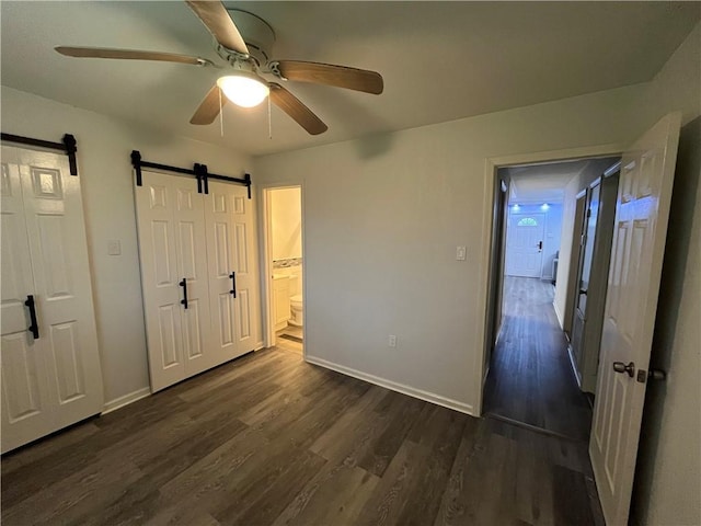 3278 Glen Eagle Ln, Kenner, LA 70065 - unfurnished bedroom featuring a barn door, dark wood finished floors, baseboards, and a ceiling fan