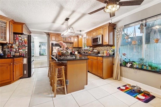 3931 S Post Oak Ave, New Orleans, LA 70131 - kitchen featuring dark countertops, stainless steel microwave, black oven, brown cabinets, and ornamental molding