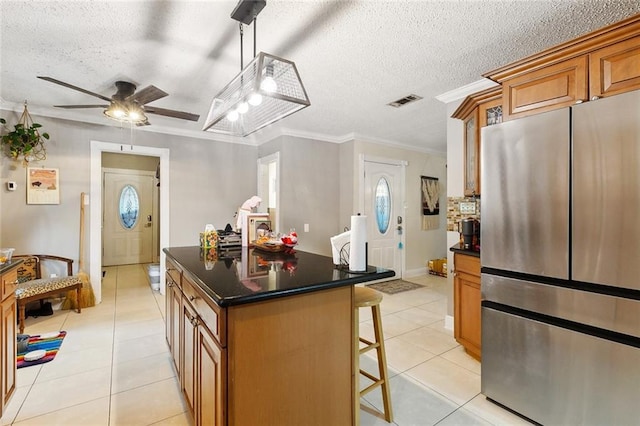 3931 S Post Oak Ave, New Orleans, LA 70131 - kitchen with freestanding refrigerator, light tile patterned floors, a kitchen breakfast bar, ornamental molding, and a textured ceiling