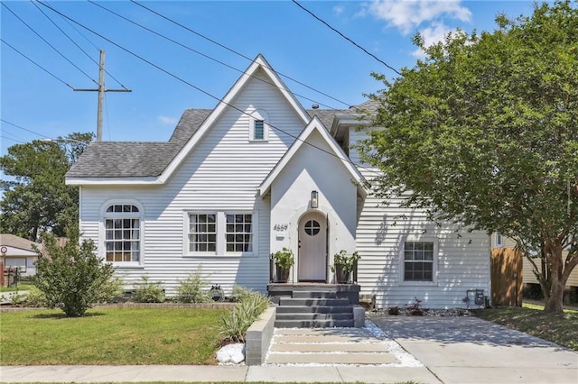 view of front facade with roof with shingles and a front lawn