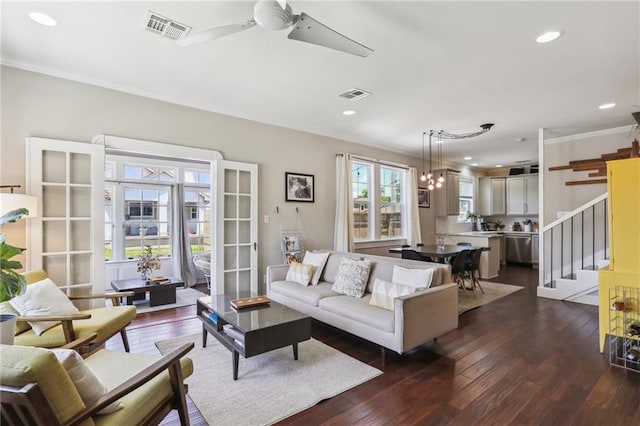 living area featuring a ceiling fan, recessed lighting, dark wood-type flooring, stairs, and ornamental molding