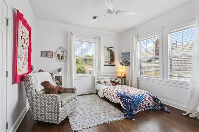 bedroom with multiple windows, wood finished floors, baseboards, and ornamental molding
