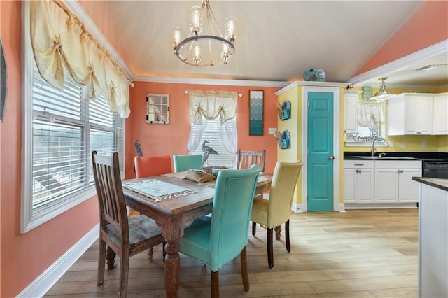 11020 Delaware St, Bay Saint Louis, MS 39520 - dining area with a chandelier, light wood-style flooring, vaulted ceiling, baseboards, and ornamental molding