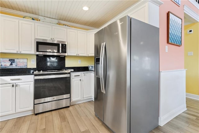 11020 Delaware St, Bay Saint Louis, MS 39520 - kitchen with stainless steel appliances, light wood-style floors, white cabinetry, ornamental molding, and backsplash