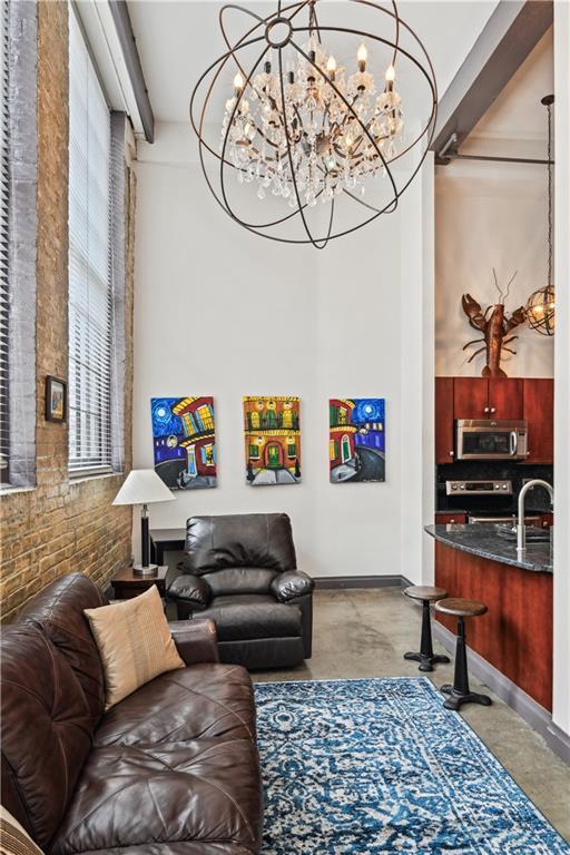 920 Poeyfarre St Unit 109, New Orleans, LA 70130 - living room with a chandelier, baseboards, and brick wall
