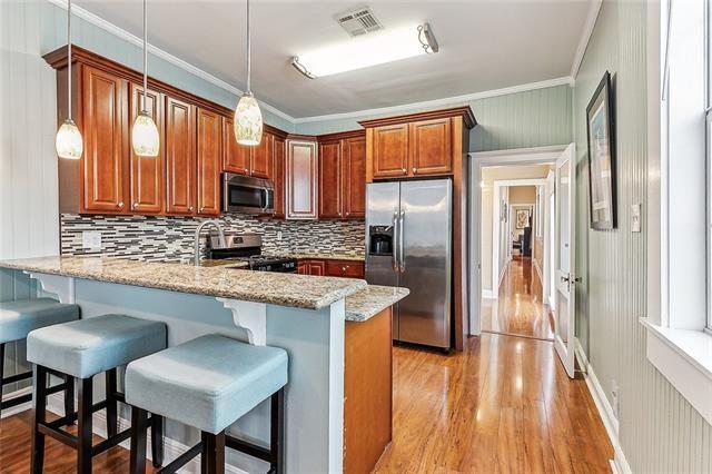 525 S Telemachus St, New Orleans, LA 70119 - kitchen featuring stainless steel appliances, a peninsula, a breakfast bar, tasteful backsplash, and light wood-type flooring