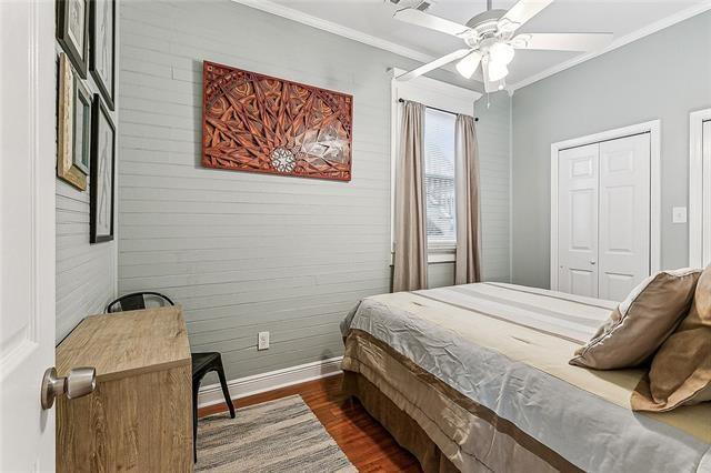 525 S Telemachus St, New Orleans, LA 70119 - bedroom featuring baseboards, crown molding, dark wood-style flooring, wood walls, and ceiling fan