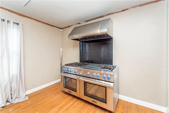 710 W Michigan St, Hammond, LA 70401 - kitchen with range with two ovens, wall chimney exhaust hood, baseboards, crown molding, and light wood-type flooring