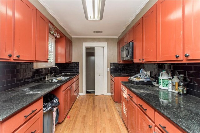 710 W Michigan St, Hammond, LA 70401 - kitchen with a sink, black microwave, light wood-style floors, tasteful backsplash, and crown molding