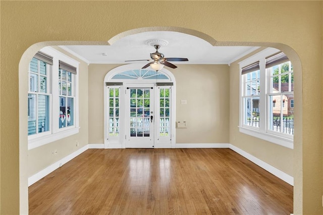 2437 Jonquil St, New Orleans, LA 70122 - doorway featuring ornamental molding, wood finished floors, baseboards, a ceiling fan, and arched walkways