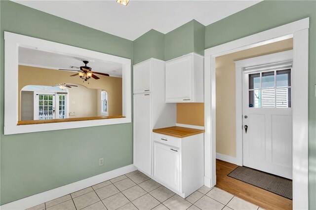 2437 Jonquil St, New Orleans, LA 70122 - kitchen featuring white cabinets, baseboards, ceiling fan, light tile patterned flooring, and light countertops