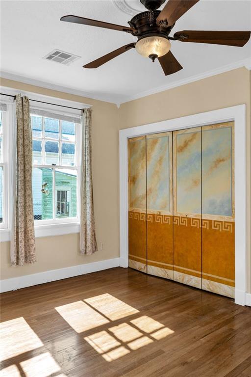 2437 Jonquil St, New Orleans, LA 70122 - unfurnished bedroom featuring wood finished floors, crown molding, baseboards, a closet, and ceiling fan