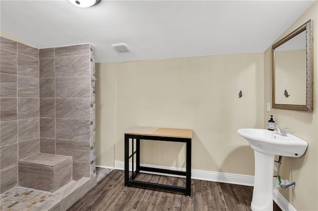 2437 Jonquil St, New Orleans, LA 70122 - full bath with wood finished floors, baseboards, a tile shower, and a sink
