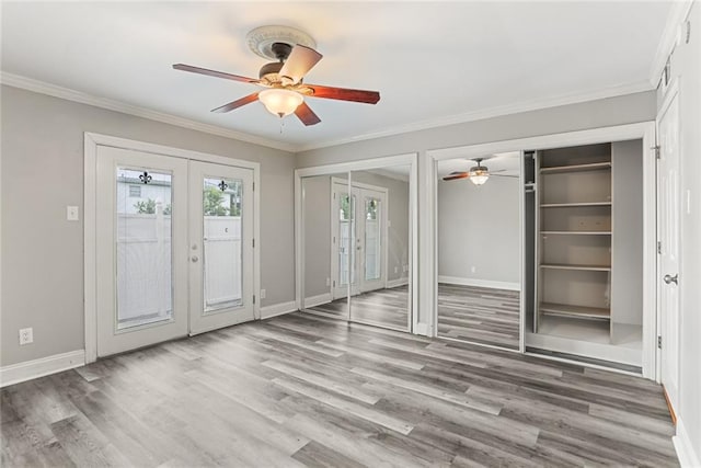 unfurnished bedroom with french doors, two closets, baseboards, and crown molding