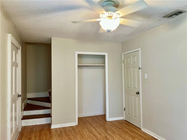 204 W 11th Ave Unit 4, Covington, LA 70433 - unfurnished bedroom featuring wood finished floors, a closet, baseboards, a textured ceiling, and ceiling fan