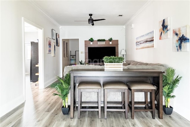 2522 Robert St, New Orleans, LA 70115 - living room featuring light wood-type flooring, crown molding, a ceiling fan, and baseboards