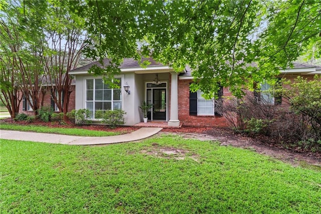 213 Secluded Oaks Ln, Madisonville, LA 70447 - view of front facade featuring a front lawn, stucco siding, a shingled roof, and brick siding