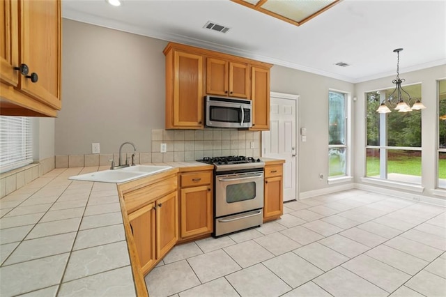 213 Secluded Oaks Ln, Madisonville, LA 70447 - kitchen with appliances with stainless steel finishes, a sink, crown molding, decorative backsplash, and a chandelier