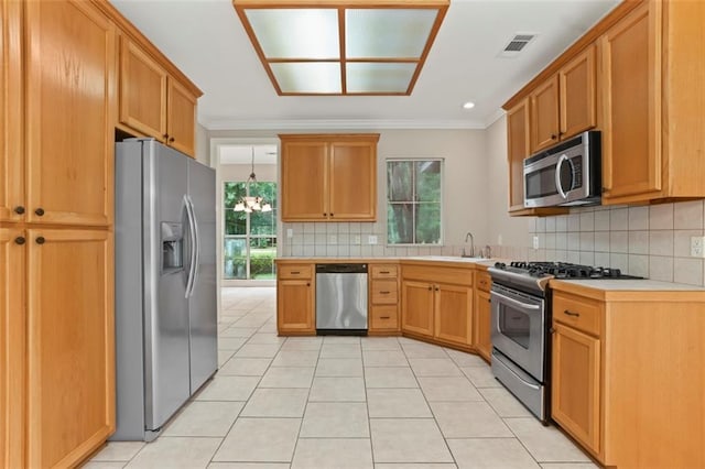 213 Secluded Oaks Ln, Madisonville, LA 70447 - kitchen with appliances with stainless steel finishes, crown molding, light countertops, decorative backsplash, and light tile patterned flooring